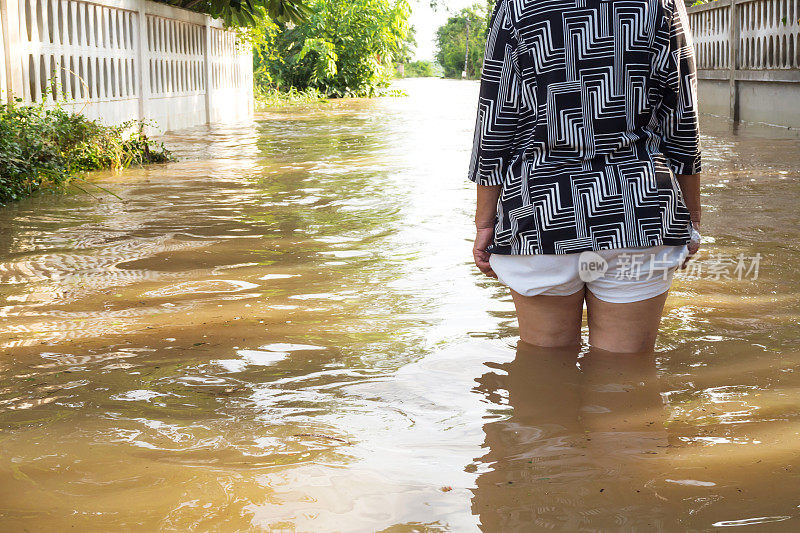 《洪水》中的女人的背影。洪水的房子。她的腿的特写。