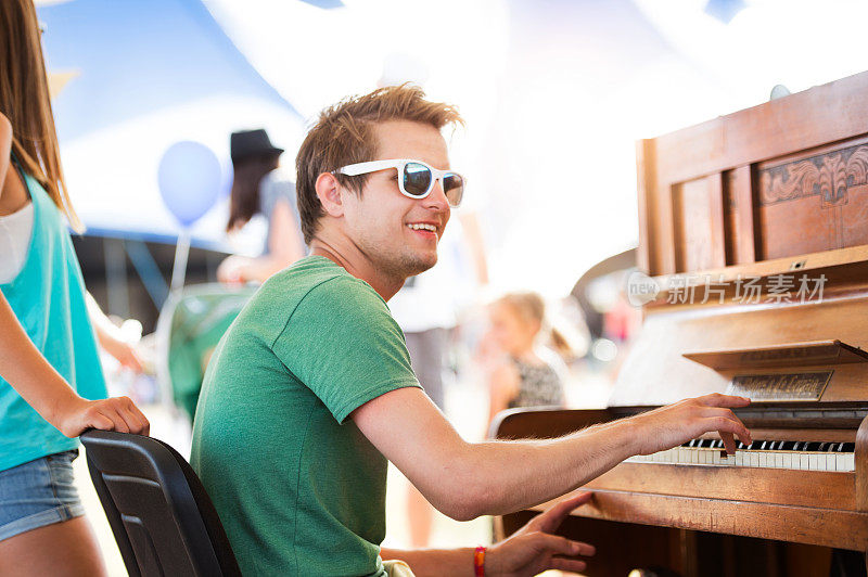 青少年情侣在夏季音乐节上，男孩弹钢琴