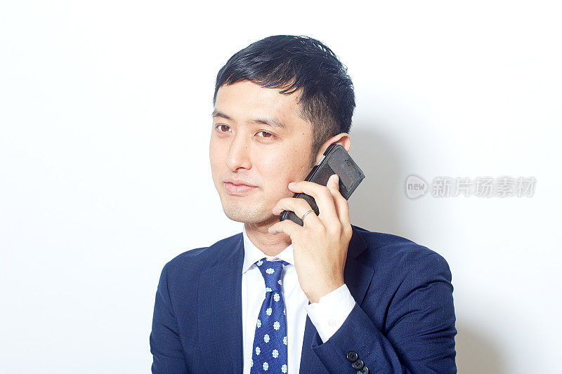 年轻的日本商人穿着西装，用智能手机聊天