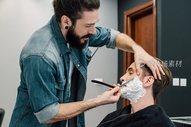 理发师在给顾客刮胡子时使用剃须刀