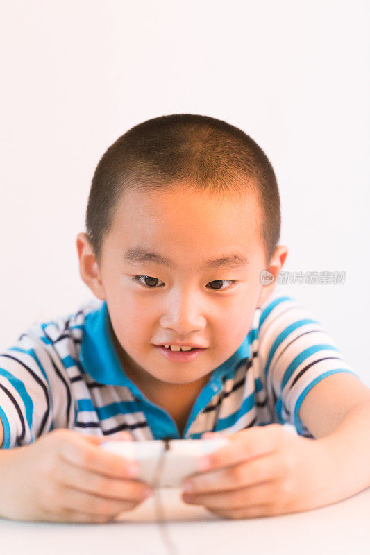 亚洲男孩与玩把手在桌子上看着相机