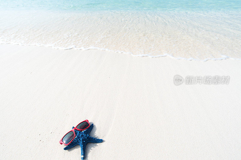 海滩假日背景——沙滩上戴着太阳镜的海星