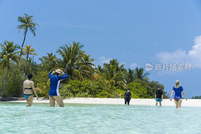 美丽的，年轻的，中年的和老年的女人和一个男人走在浅水的沙滩上，四月，马尔代夫