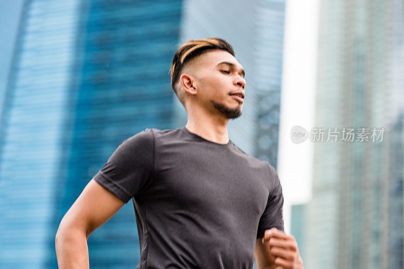 一名亚洲男子在城市中奔跑，背景是天际线