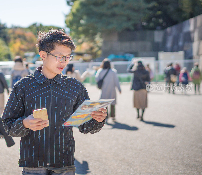 年轻的亚洲男子和日本朋友寻找旅游地点使用手机和花时间在亚洲旅行