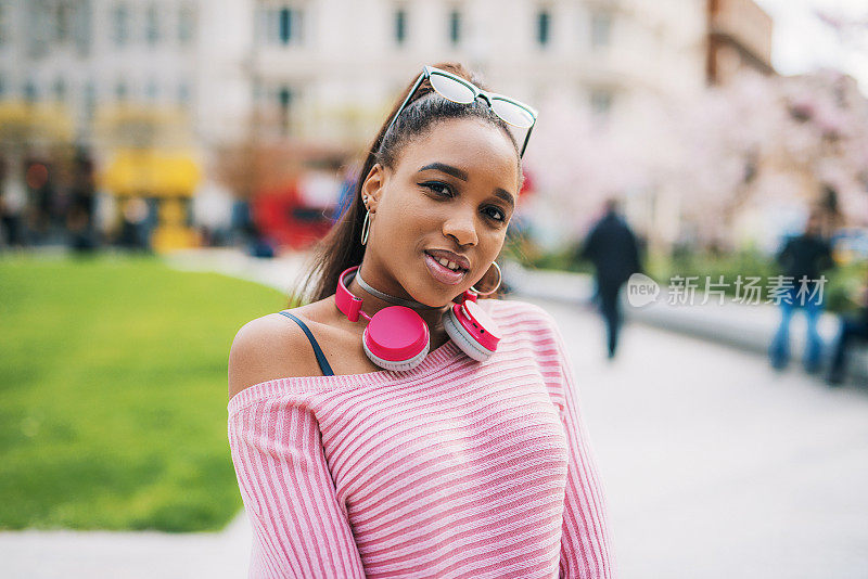 Z一代非洲裔女性戴着耳机，享受城市的春天