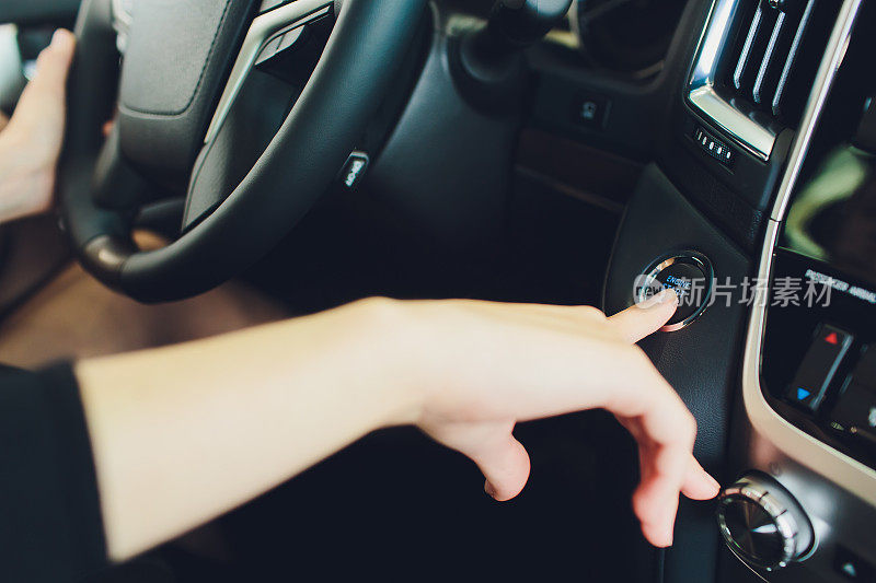 女人用起停按钮启动汽车引擎。现代汽车内饰。
