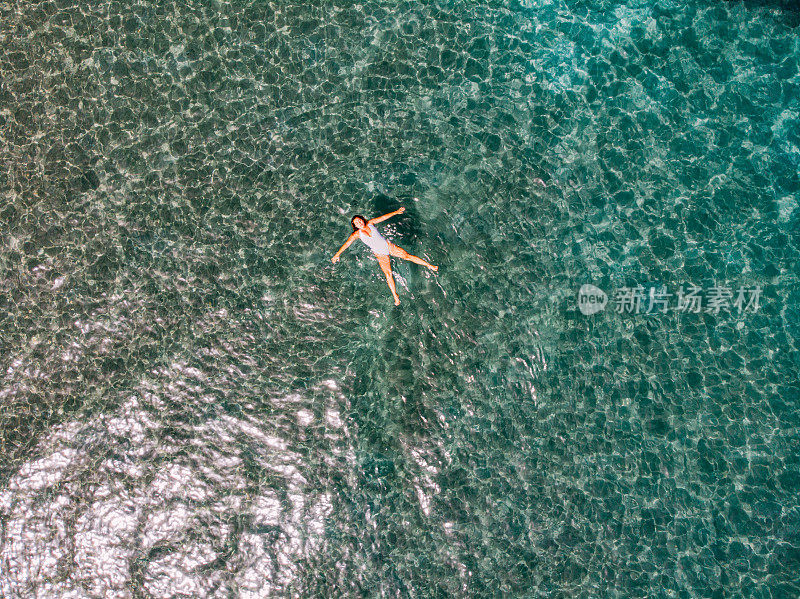 鸟瞰图女人漂浮在清澈的大海