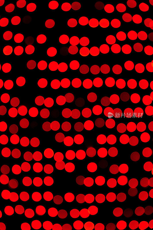 无焦点的抽象红色散景在黑色背景上。散焦和模糊了许多圆光