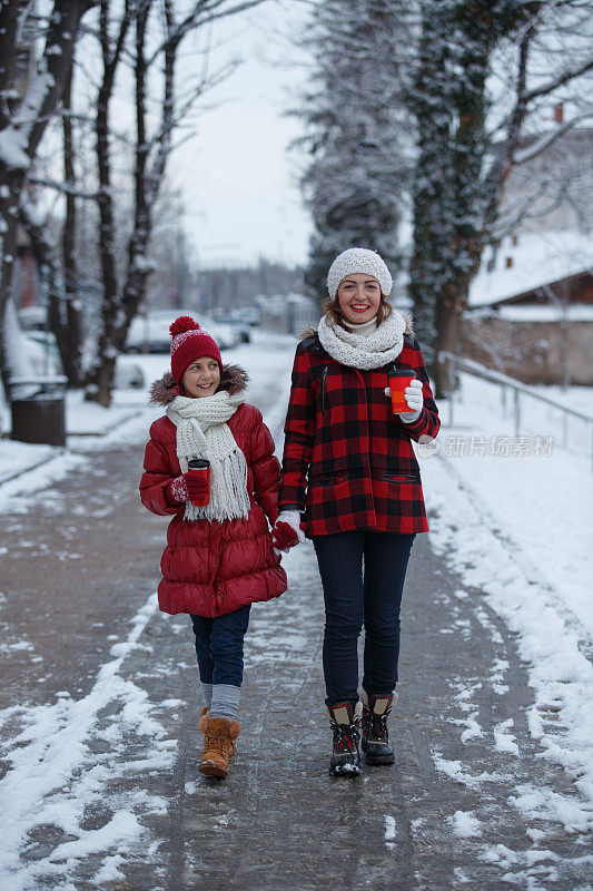 母亲和女儿在公园散步，在一个下雪天喝茶