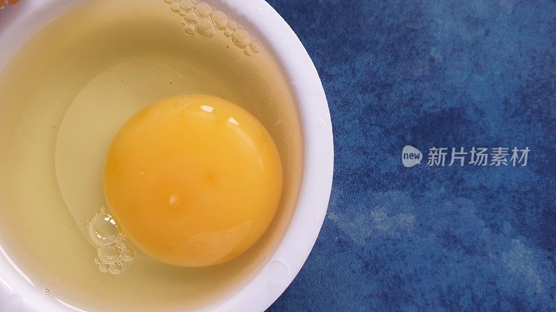 水煮菜中的生鸡蛋在蓝色背景上，并留有拷贝空间