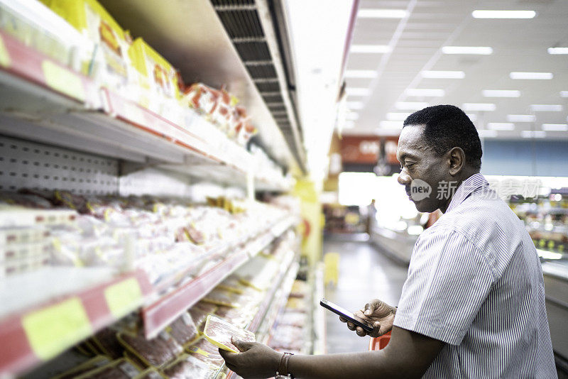 成熟的男人在超市购物，用智能手机扫描条形码