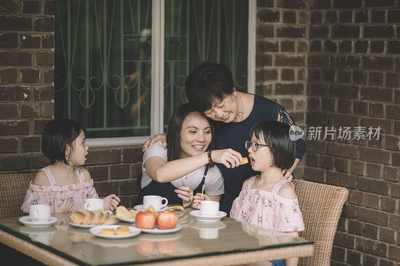 一个亚洲华人家庭在前院和祖父母一起喝茶