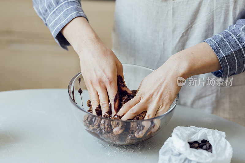 手的一个不认识的女人混合黑巧克力到巧克力薄片曲奇面团，一个近距离