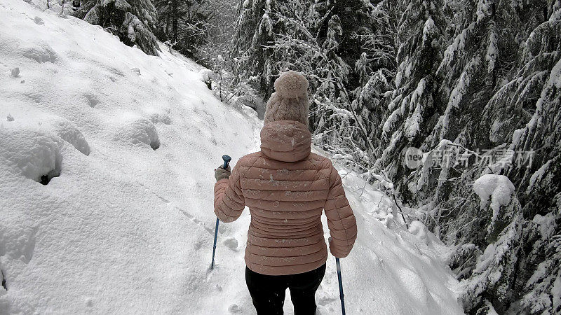 女性徒步旅行者沿着雪道行走