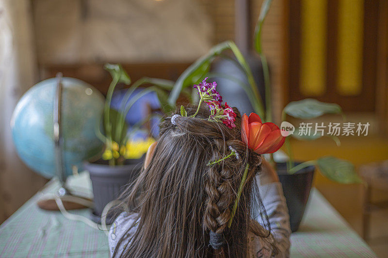 一个头发上戴着花的小女孩的后视图肖像