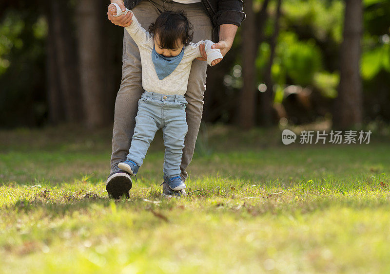 爸爸在后院帮小男孩练习走路