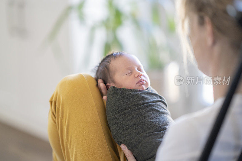 白人母亲抱着襁褓中的新生儿