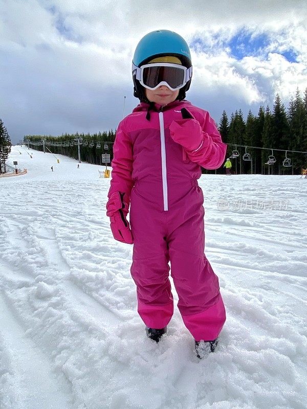 在滑雪胜地穿着滑雪服的小女孩。