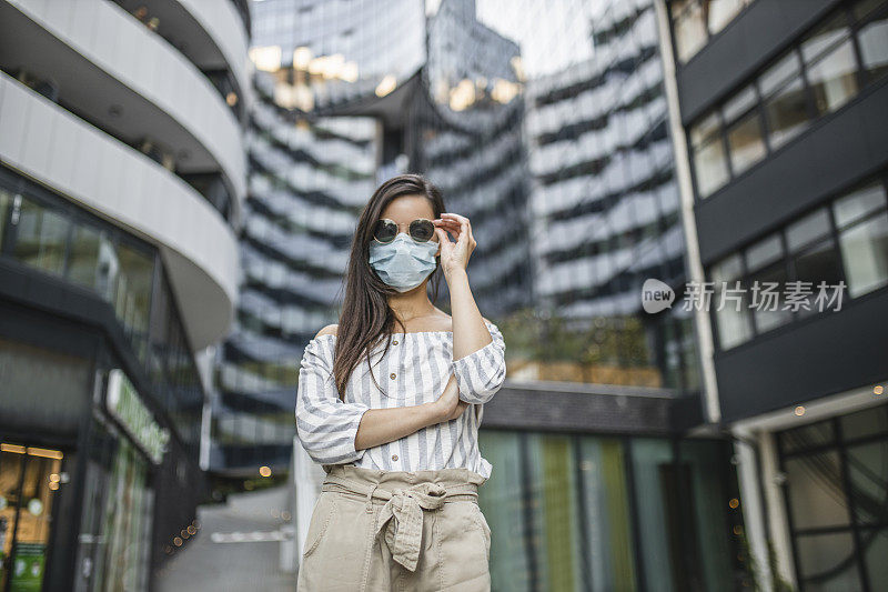 在新冠肺炎大流行期间，美丽的年轻女子戴着医疗脸在城市的肖像