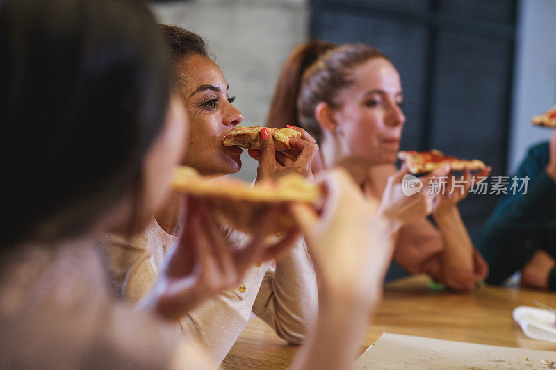 年轻女性在午餐休息时间享用披萨片