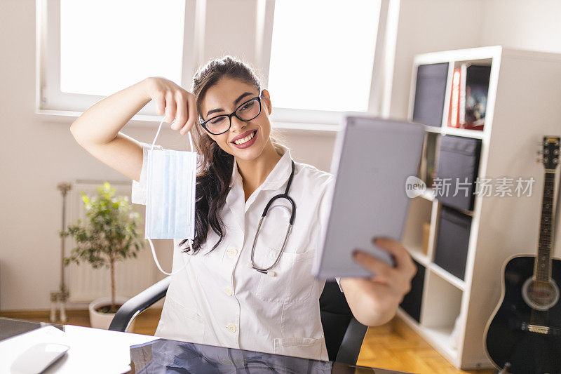 在冠状病毒大流行期间，年轻女医生正在用电子平板电脑与患者视频通话