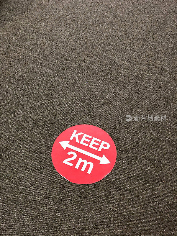 水泥地面红白圆形贴纸上的箭头、冠状病毒社交距离规定保持2米距离、冠状病毒安全、高架视野
