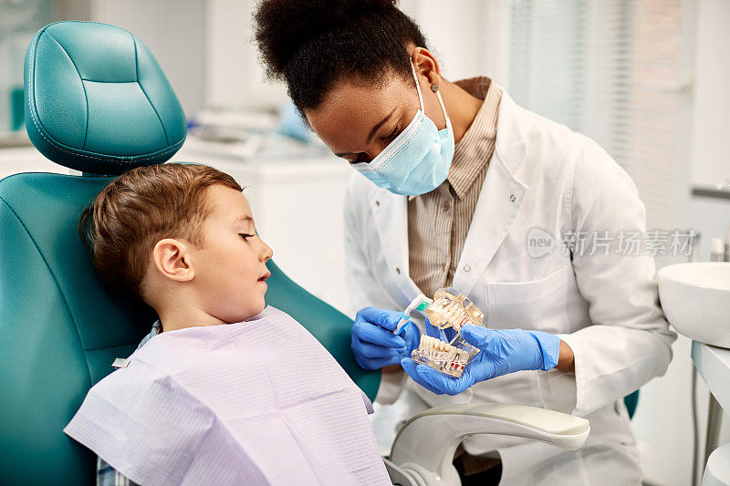 非裔美国牙医教小男孩在看牙医时如何正确刷牙。