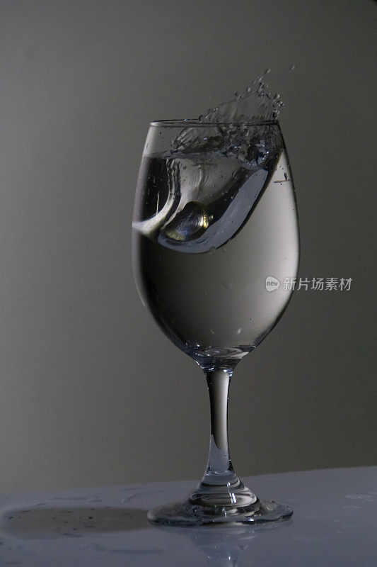 硬币掉进一只盛满水的玻璃杯里