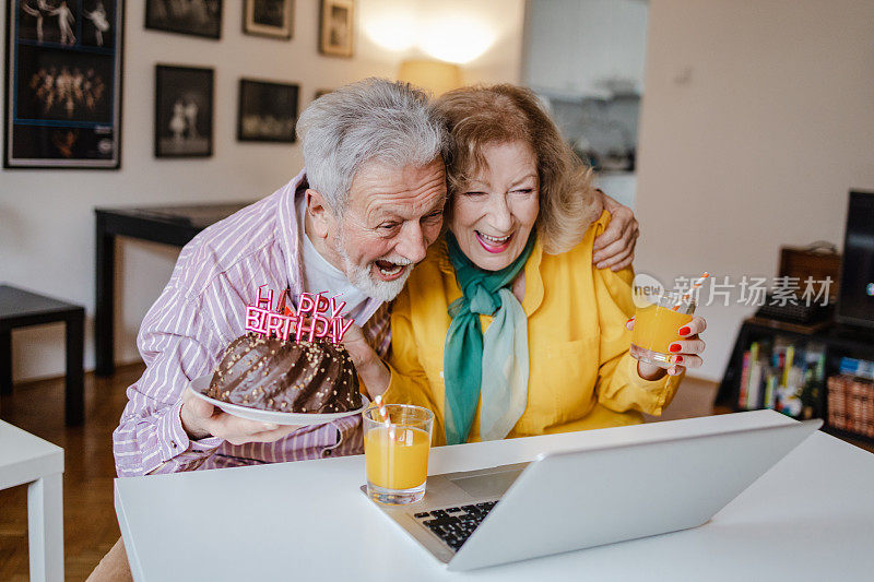 一对老年夫妇正在家里通过视频电话庆祝生日