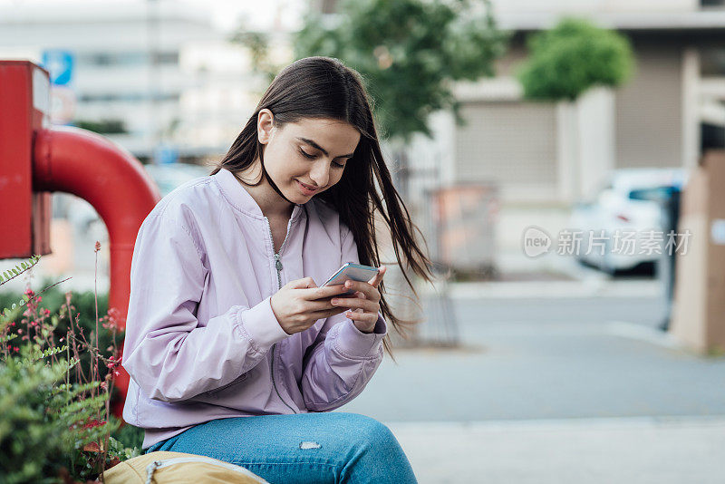 一个女孩在街上用智能手机的照片