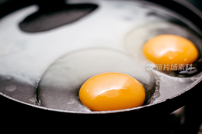 两个单面煎蛋，放在黑锅里煮