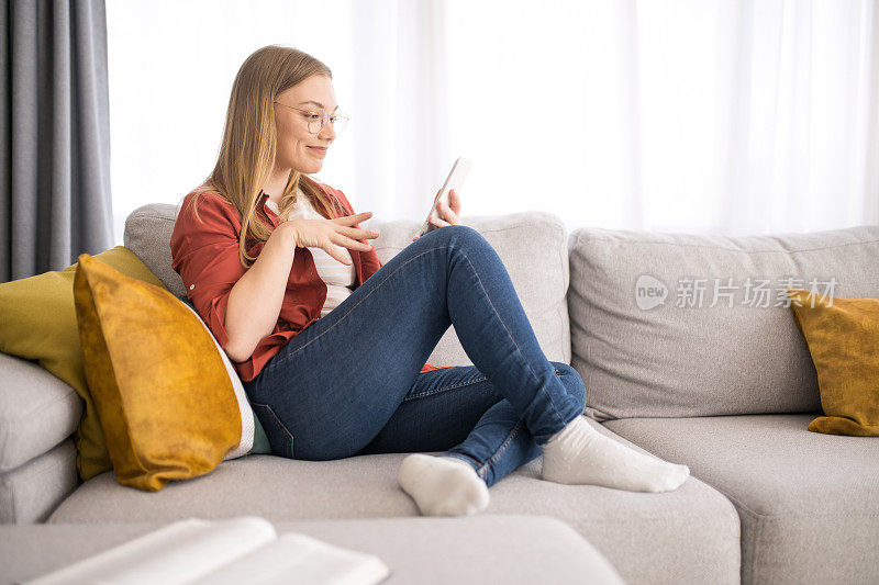 犹豫不决的年轻女子一边在家看手机一边选择。