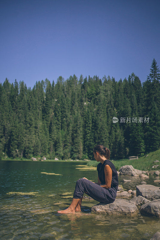 女徒步旅行者放松附近的高山湖泊早上