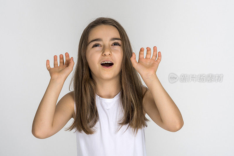 可爱的女孩张开嘴，抬头，举起双手，张开手掌