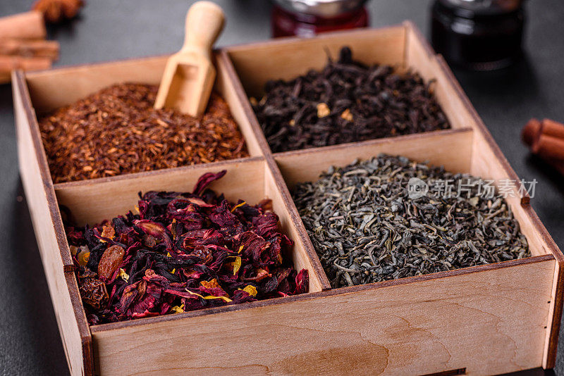 几种干红茶与佛手柑，rooibos，绿色和框架在一个黑色混凝土背景的木制盒子