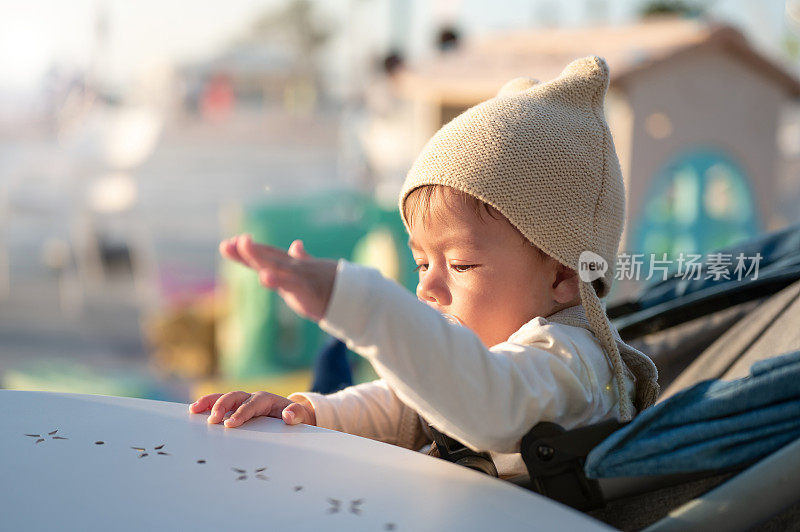 小男孩坐在户外的咖啡吧里，靠在桌子上