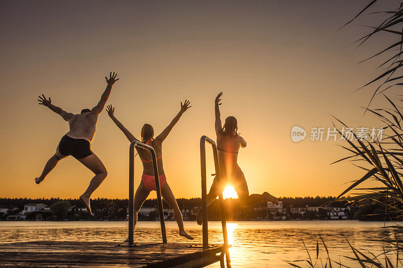 一群朋友在日落时分跳入湖中