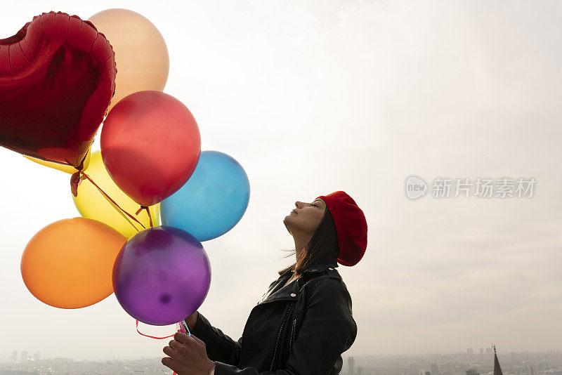 女人举着五颜六色的气球冲向天空