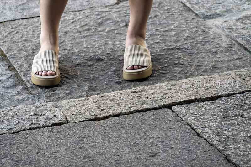 穿着拖鞋的女人站在石板路上