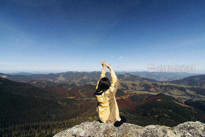 一个女人坐在悬崖边，欣赏着山景