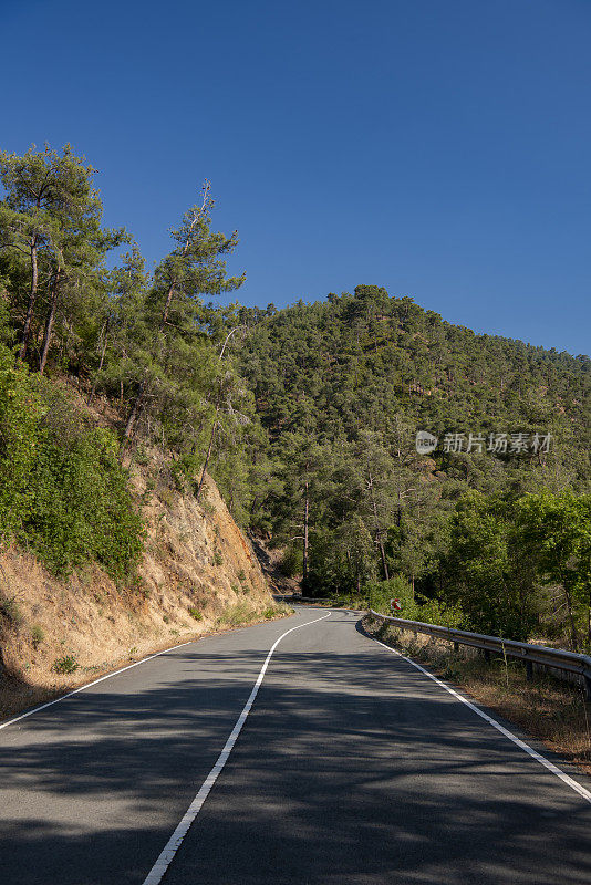 蜿蜒的道路穿过陡峭的火山地形，前方山峰高耸，右侧有护栏