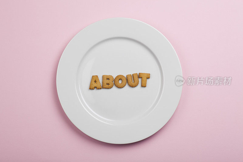白色盘子上有饼干字母“about”;粉红色的背景