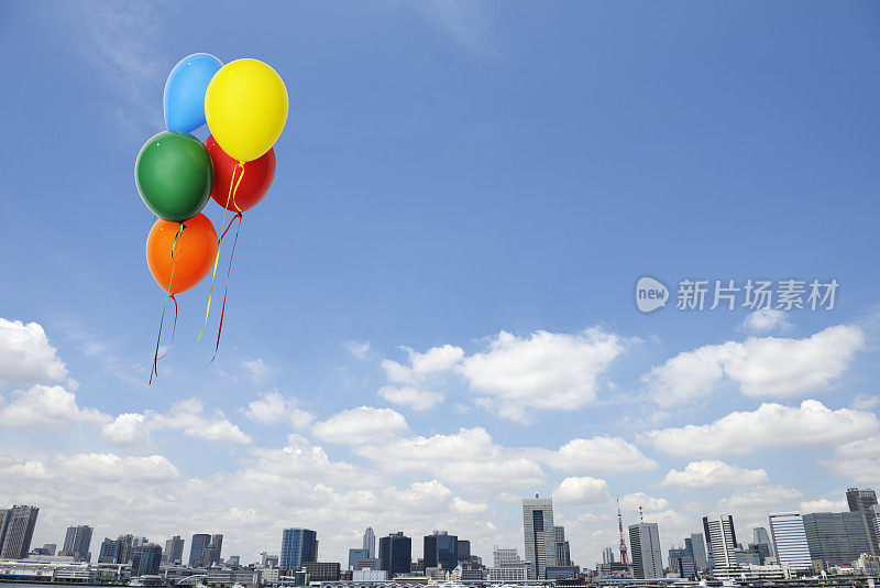 五颜六色的气球漂浮在城市清澈的天空中
