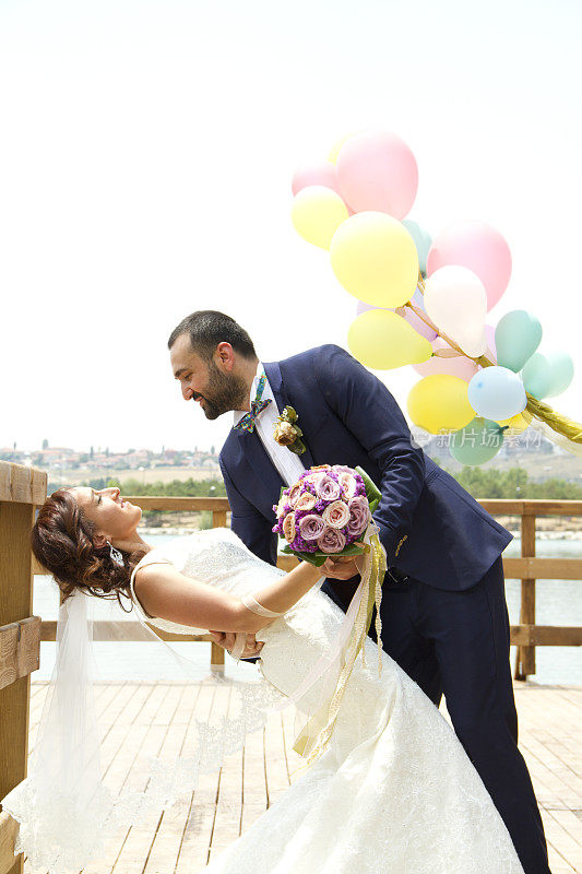 快乐的新婚夫妇在码头上用彩色气球跳舞