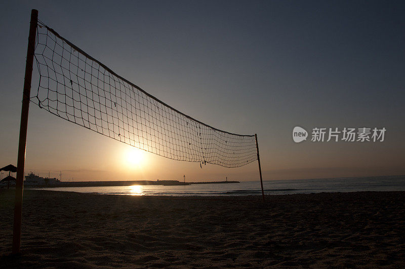 日出在海滩排球场与太阳和网