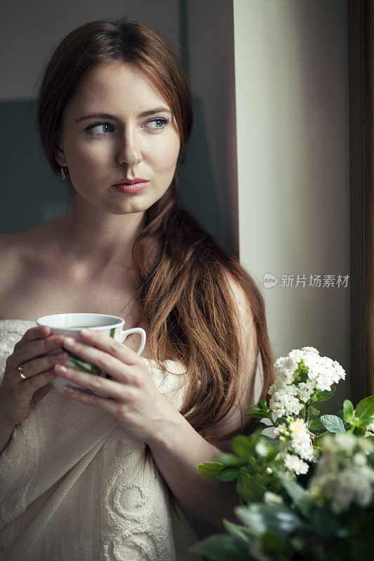 在窗口喝茶的年轻女子