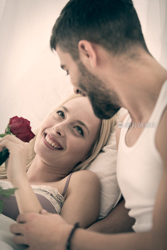 男人在床上给女朋友玫瑰