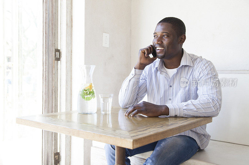 一个非洲人坐在咖啡馆里讲电话