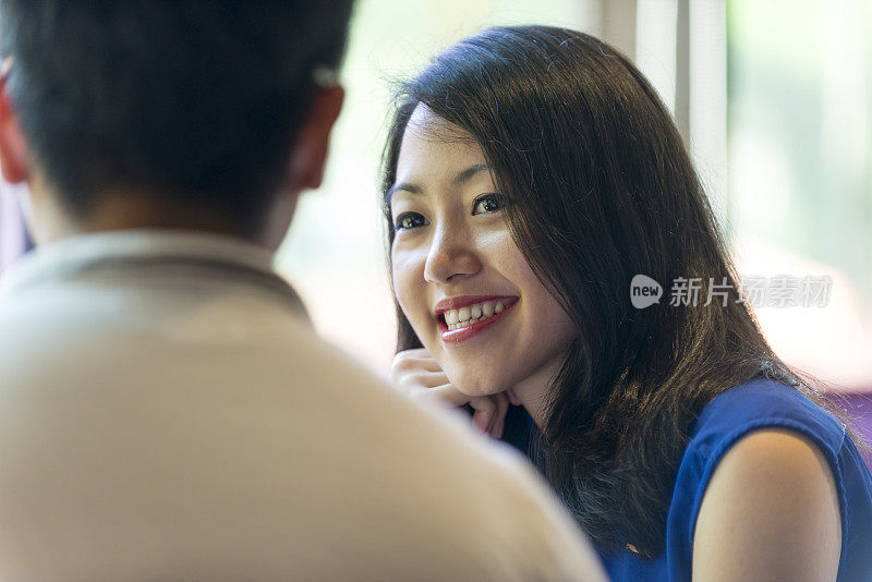 快乐的年轻亚洲夫妇在咖啡馆聊天